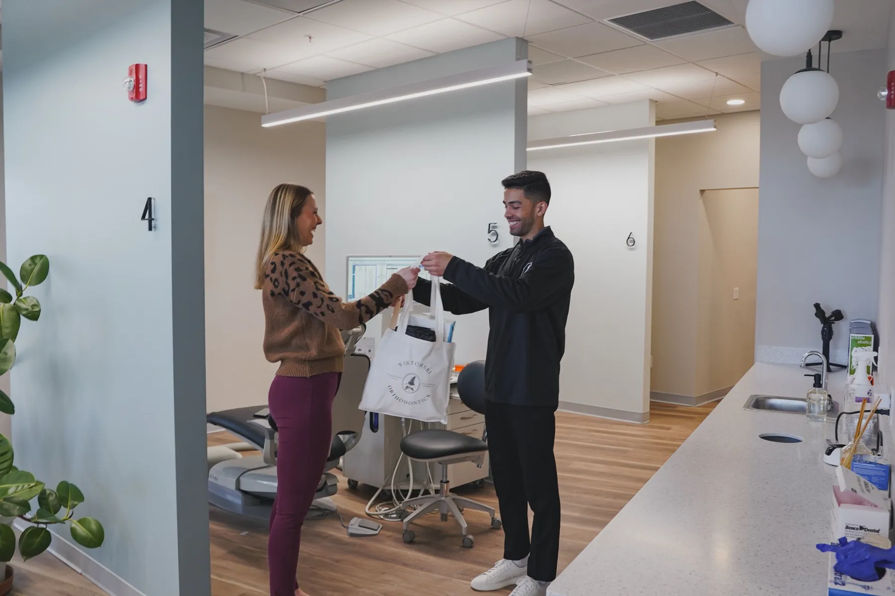 Dr. Wiktorski handing an adult patient a Wiktorski Orthodontics welcome bag