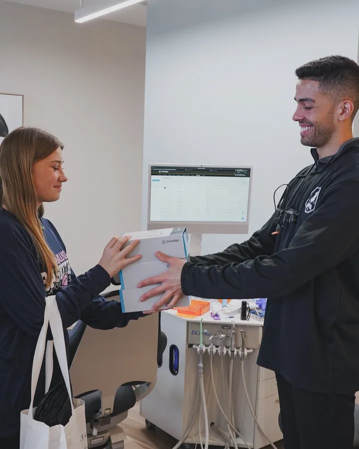Dr. Wiktorski handing a teen patient her new Invisalign aligners