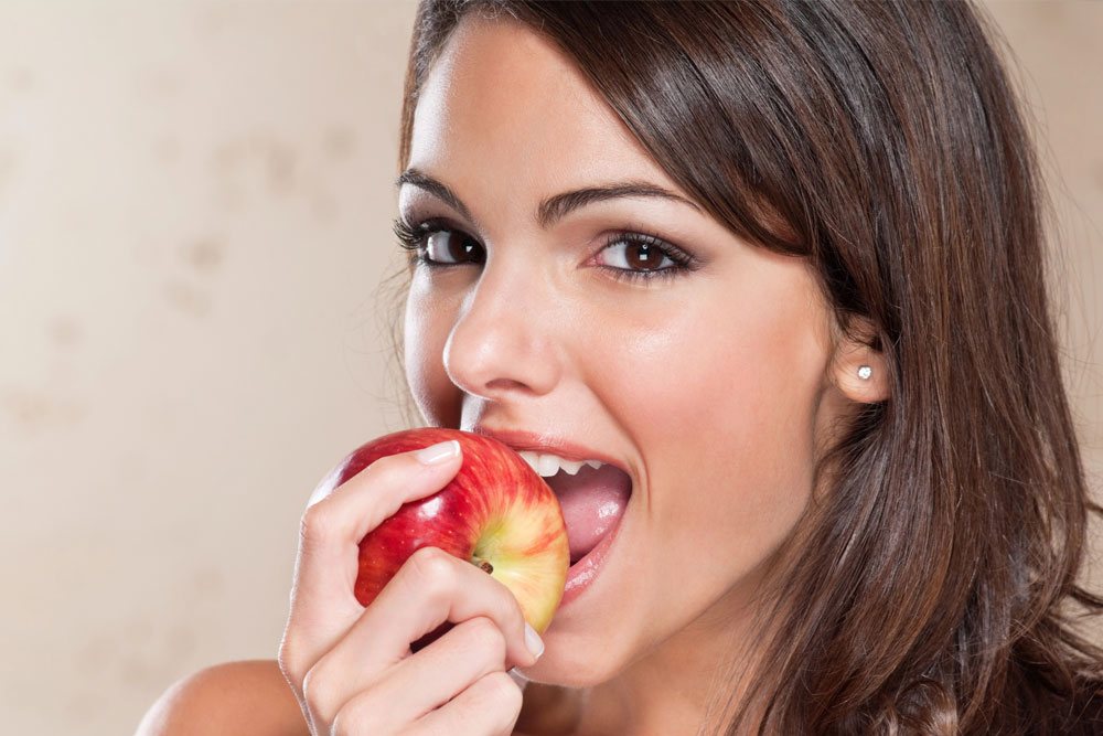 Smiling young woman eating apple | Orthodontic nutrition