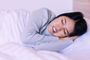 Young woman suffering from bruxism while sleeping