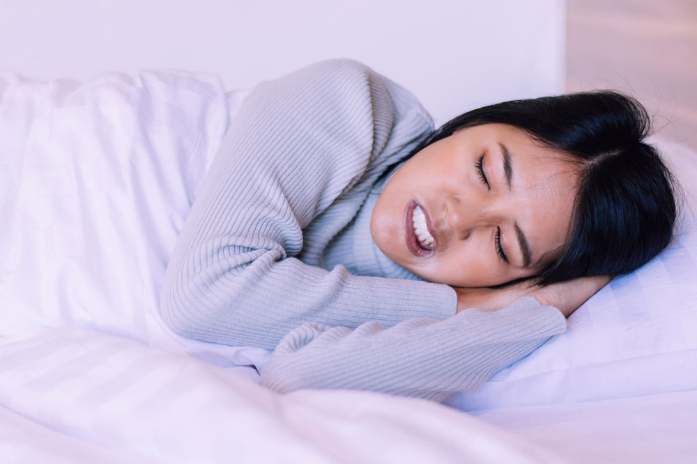 Young woman suffering from bruxism while sleeping