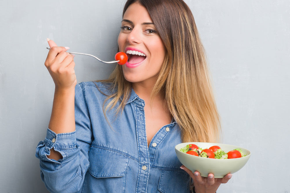 Young woman eating salad | Orthodontic Diet Success in Rochester, NY